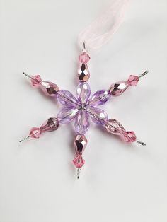 a snowflake ornament with pink and purple beads