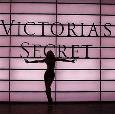 a woman standing in front of a sign that says victoria's secret