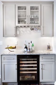 a wine rack in the middle of a kitchen with white cabinets and wood flooring