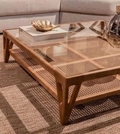 a glass coffee table sitting on top of a carpeted floor next to a couch