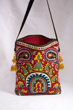 "Large Rectangular Flat Zipper Top Silk Petit Point Handbag created and handmade in Uzbekistan. Lined with silk ikat fabric, hand woven silk straps and tassels and a magnetic snap closure. Each handbag is hand drawn onto cotton canvas, inspired by original designs from Uzbekistan textile history.  11.5\" high x 9.5\" width, top opening 9\" wide,  approx. 54\" strap x 3/4\" width.  Can fit largest sizes of iPhone and Android. 100% silk petit point with handwoven silk ikat lining. Your purchase pr Traditional Bags With Multicolor Embroidery And Motifs, Traditional Rectangular Shoulder Bag With Motifs, Traditional Bag With Multicolor Embroidery, Traditional Shoulder Bag For Travel, Traditional Embroidered Shoulder Bag With Motifs, Traditional Rectangular Shoulder Bag With Intricate Embroidery, Traditional Multicolor Embroidered Bag, Artisan Red Embroidered Bag, Red Rectangular Bags With Motifs