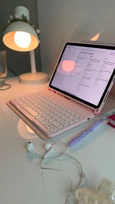 an open laptop computer sitting on top of a white desk next to a lamp and other items