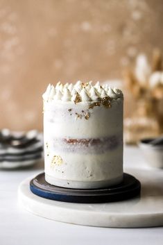 a cake with white frosting and gold sprinkles sitting on a plate