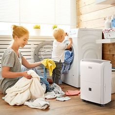 two young children are playing with clothes in the washing machine while another child looks on