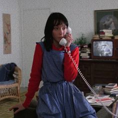 a woman is talking on the phone while sitting in a living room with an old fashioned telephone