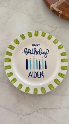 a happy birthday plate with candles on it sitting on a marble counter top next to a cutting board