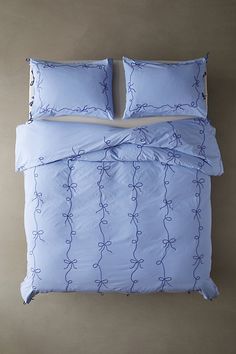 a bed with blue sheets and pillows on top of it, next to a wall