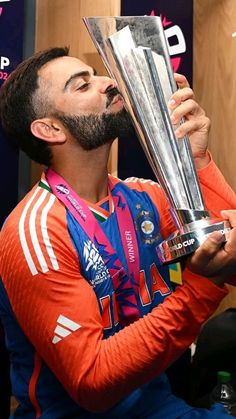 a man with a beard holding up a trophy in front of his face while sitting down