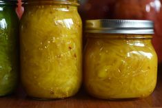 three jars filled with yellow and green pickles