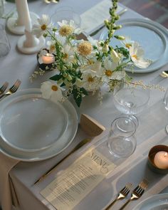 a table set with plates, silverware and flowers