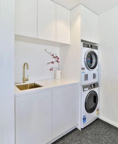 a washer and dryer in a small room with white cabinets on the walls