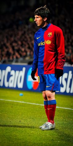 a man standing on top of a soccer field holding a ball in his hand and looking off to the side