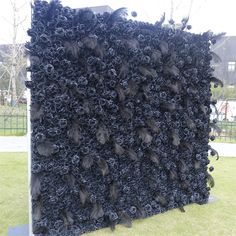 a large black piece of art sitting on top of a grass covered field