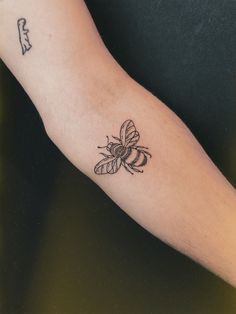 a small bee tattoo on the left arm