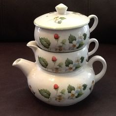 three teapots are stacked on top of each other with flowers painted on them