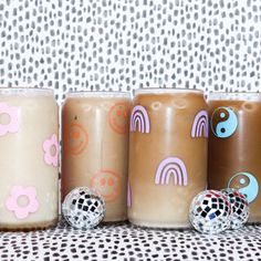 four coffee mugs with designs on them are lined up against a patterned wallpaper