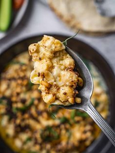 a spoon full of cauliflower with bread in the background