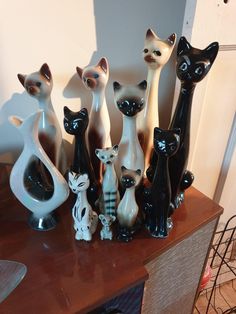 a group of black and white cat figurines on top of a wooden table