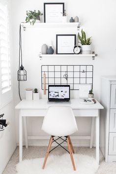 a white desk with a laptop on it and some plants in the corner next to it