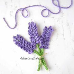 crocheted lavender flowers are displayed on a marble surface with twine and thread