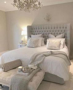 a bedroom with a large bed, chandelier and white carpeted flooring