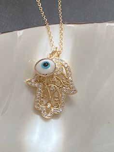 Beautifully CZ embedded gold hamsa hand pendant with Blue evil eye charm on 18K gold filled chain. HAMSA HAND Depicting the open right hand, an image recognized and used as a SIGN OF PROTECTION in many societies throughout history, the HAMSA is believed to provide defense against the evil eye. *Hamsa Hand Charm measures 20mm x 17mm ---------------------------------------- *JEWELRY CARD OPTIONS* Please indicate your choice of a message or your personals message in the 'message to seller' box as y Gold Evil Eye Necklace As Gift, Gold Plated Evil Eye Charm Necklace Gift, Gold Evil Eye Pendant Charm Necklace, Blue Evil Eye Necklace, Blue Evil Eye Metal Necklace, Blue Metal Evil Eye Necklace, Spiritual Evil Eye Metal Necklace, Evil Eye Hamsa, Hamsa Necklace Gold