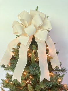 a decorated christmas tree with lights and a large white bow on it's top