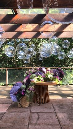 some clear bubbles hanging from the ceiling above a table with flowers and vases on it