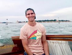 a man sitting on the back of a boat in the water smiling at the camera