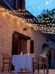 an outdoor dining area with lights strung over it