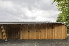 a large wooden building sitting next to a lush green forest