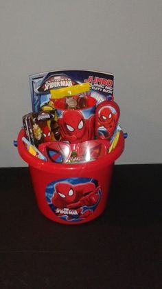 a red basket filled with candy and candies on top of a wooden table next to a wall