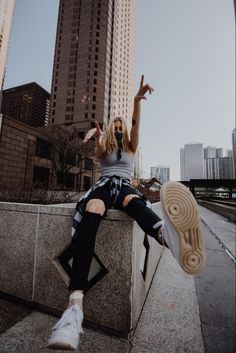 a woman sitting on top of a cement wall next to tall buildings