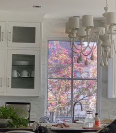 a kitchen with white cabinets and a chandelier hanging from it's ceiling