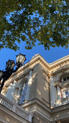 an old building with two lamps on the front and one lamp on the side, against a blue sky