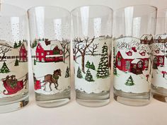 four glasses with christmas scenes painted on them