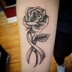 a rose with a ribbon tattoo on the arm