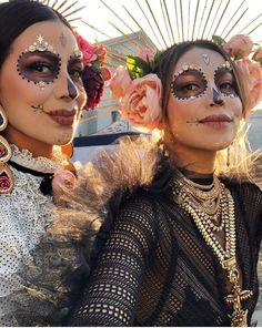 two women with face paint and flowers on their heads are posing for a photo together