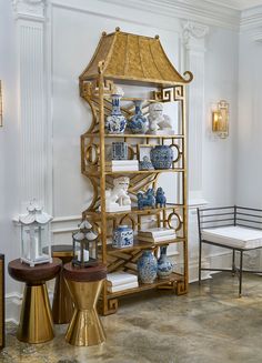 a gold shelf with blue and white vases on it in the corner of a room