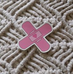 a pink sticker sitting on top of a pile of white knitted material with a heart in the middle