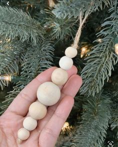 a hand is holding some beads on a christmas tree