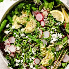 a salad with radishes, avocado and feta cheese in a white bowl