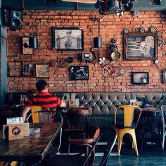 a man sitting at a table in front of a brick wall with pictures on it