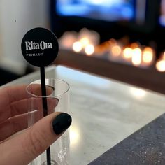 a person holding a drink in their hand with a black stick sticking out of it