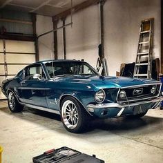 an old blue mustang in a garage with tools