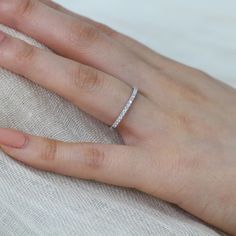 a woman's hand with a diamond ring on top of her left hand, resting on a pillow