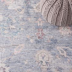 a ball of yarn sitting on top of a blue and pink rug with floral designs