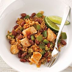 a white bowl filled with rice and beans next to a lime wedge on the side