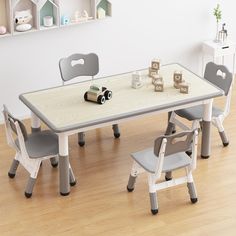 a child's table and chairs with toy cars on the wooden floor in front of a white wall