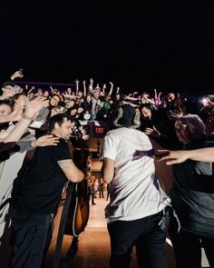 a group of people standing next to each other in front of a crowd at night